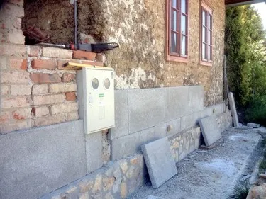 Základová stěna domu s kamenným obkladem a dlažbou.