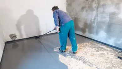 Pracovník nanáší epoxidovou podlahu válečkem na beton.