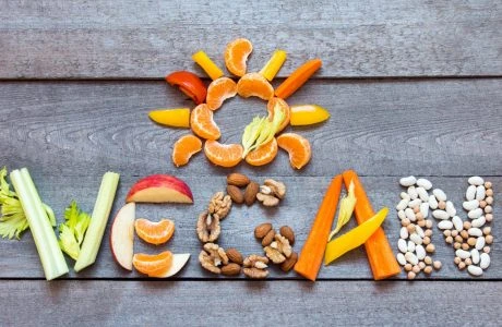 Různé ovoce a zelenina tvořící slovo vegan na dřevěném povrchu.
