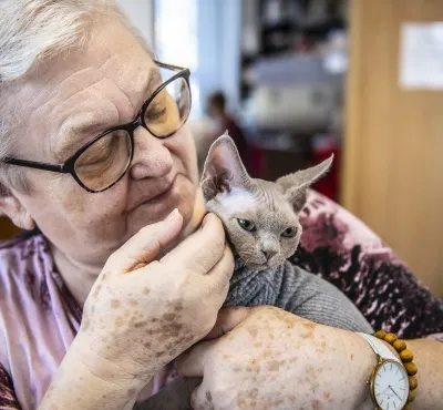 Starší žena drží kočku při felinoterapii