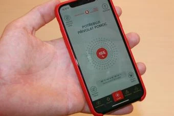 Ruka drží chytrý telefon s aplikací pro první pomoc při tonutí.