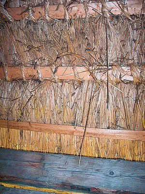 Detail doškové střechy s trávy upevněné dřevem.