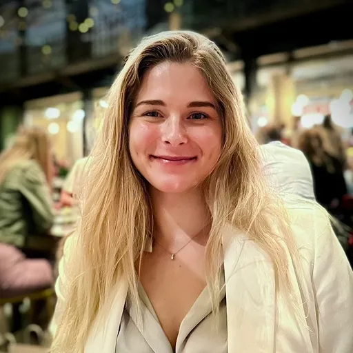 Usměvavá žena s dlouhými blond vlasy v interiéru.