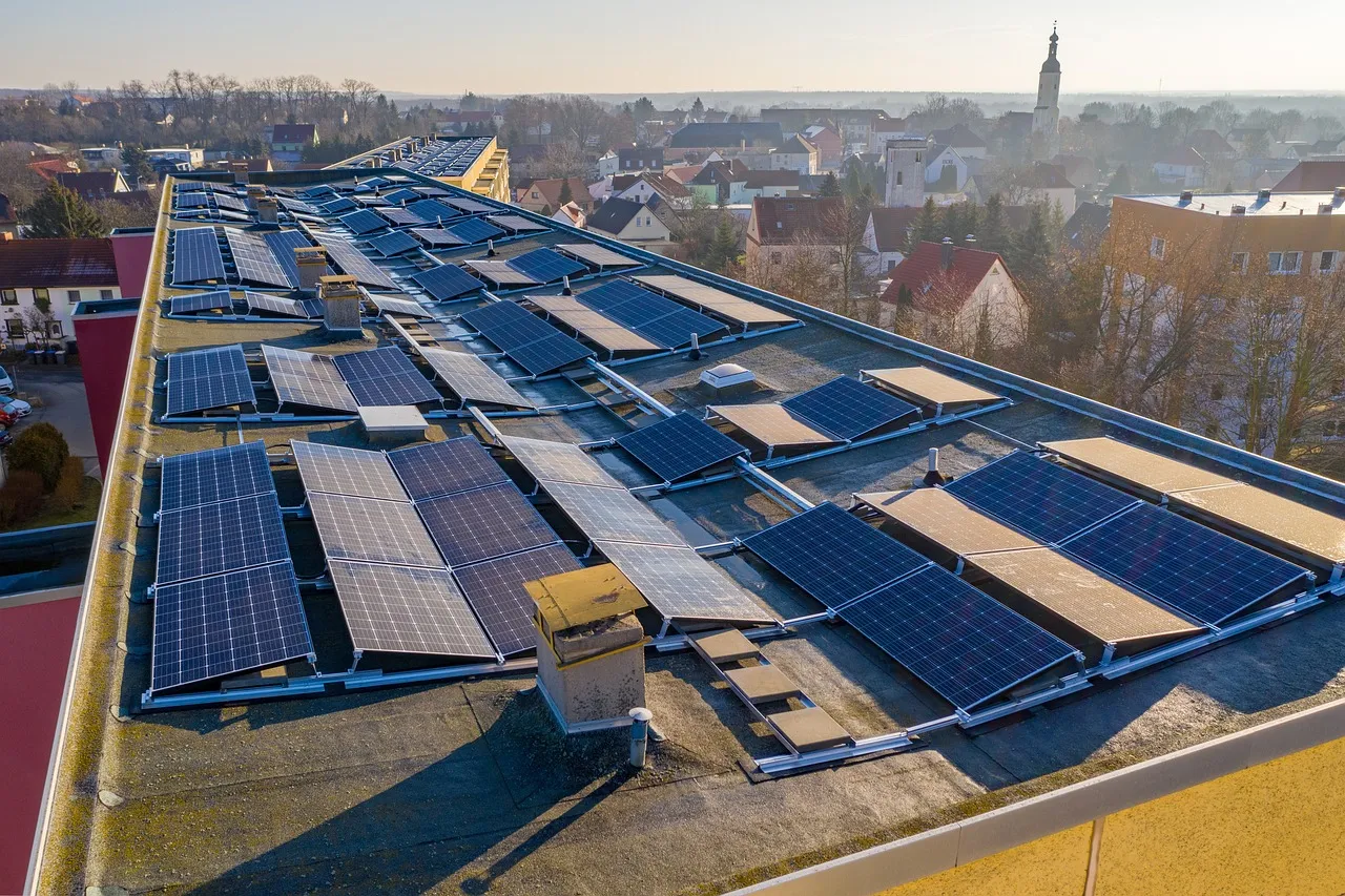 Fotovoltaické panely na střeše budovy v městském prostředí.