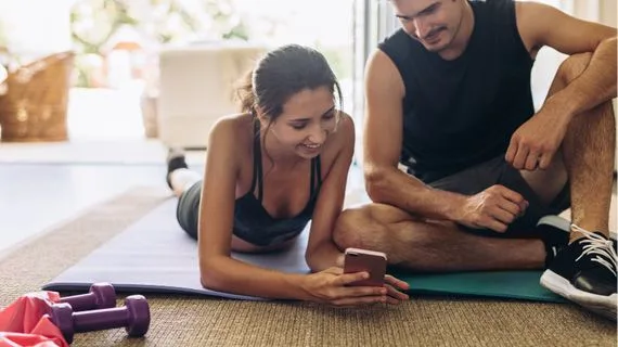 Muž a žena cvičí v interiéru s mobilním telefonem.