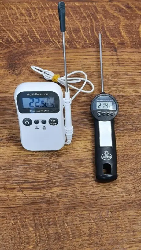 Dva digitální teploměry pro temperování čokolády na dřevěném povrchu.